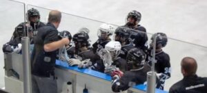 coach with lacrosse players at the bench